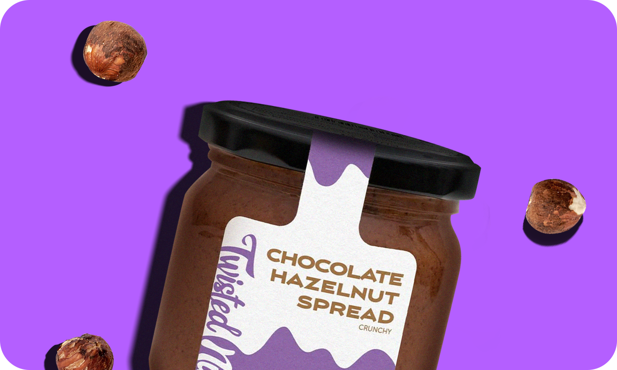 Chocolate Hazelnut Spread Glas liegt mit Haselnüssen auf violettem Hintergrund